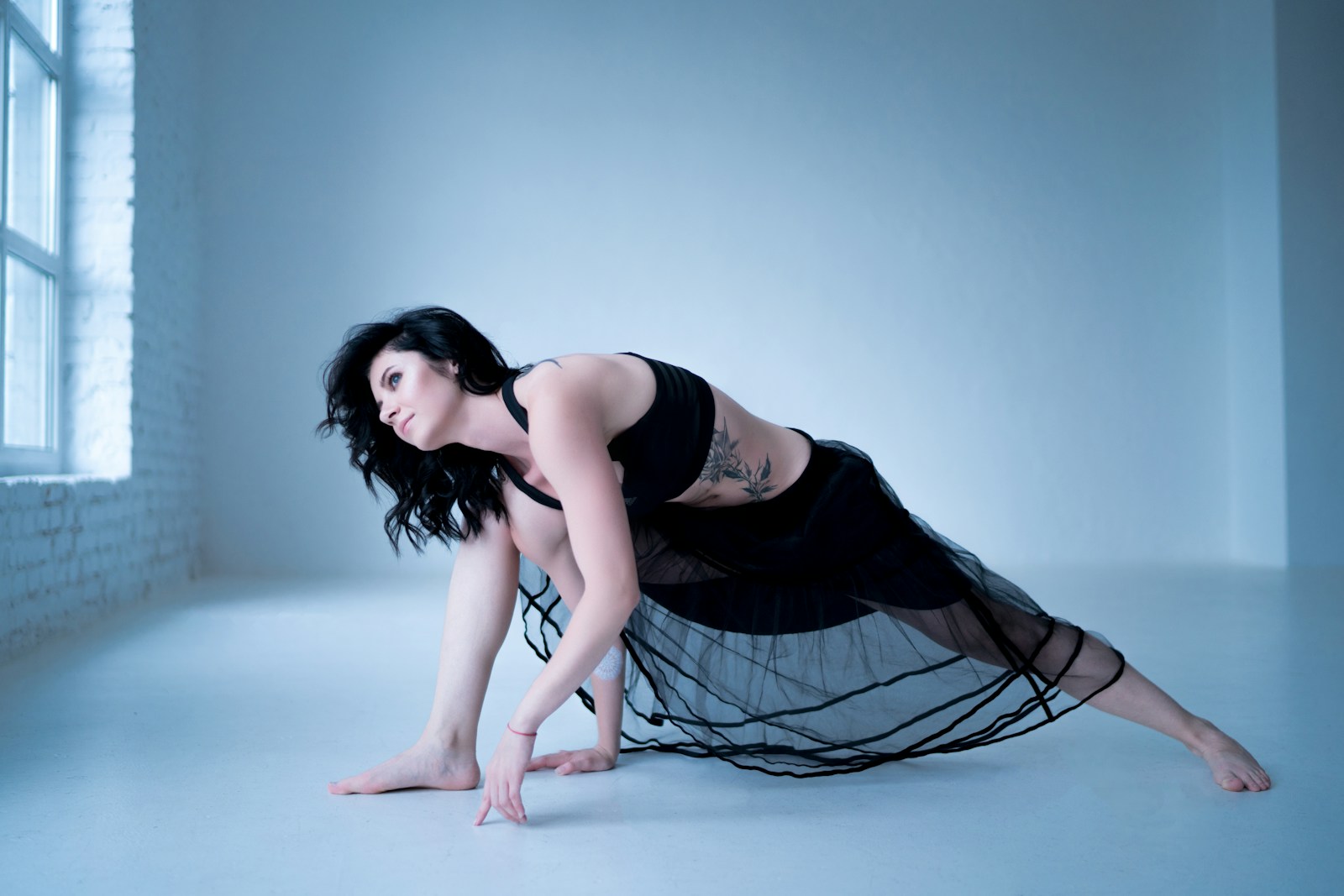 Photo by Oksana Taran woman in black tank top and black and white skirt lying on blue floor
